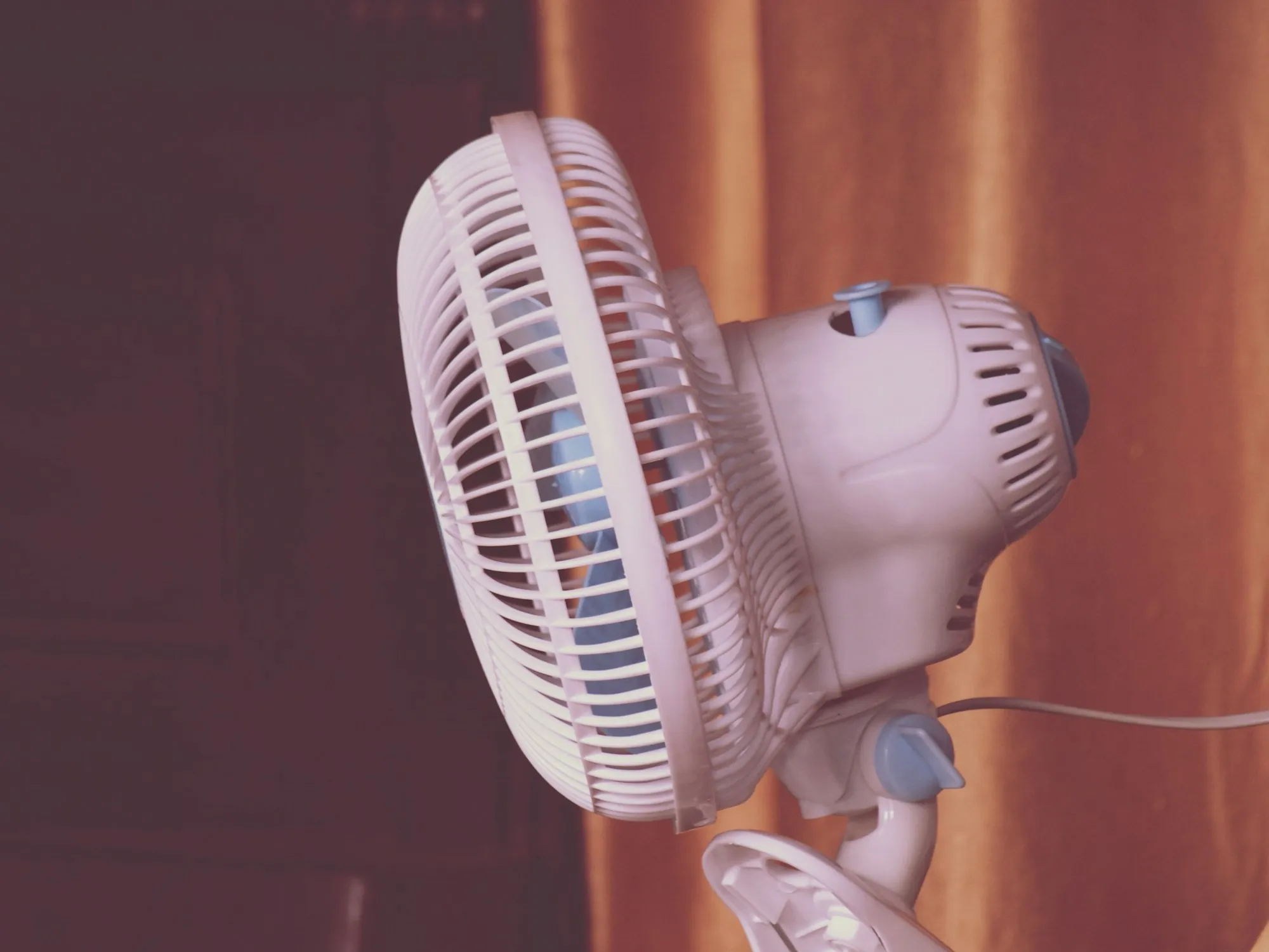 Pink electric fan blowing in a warm room